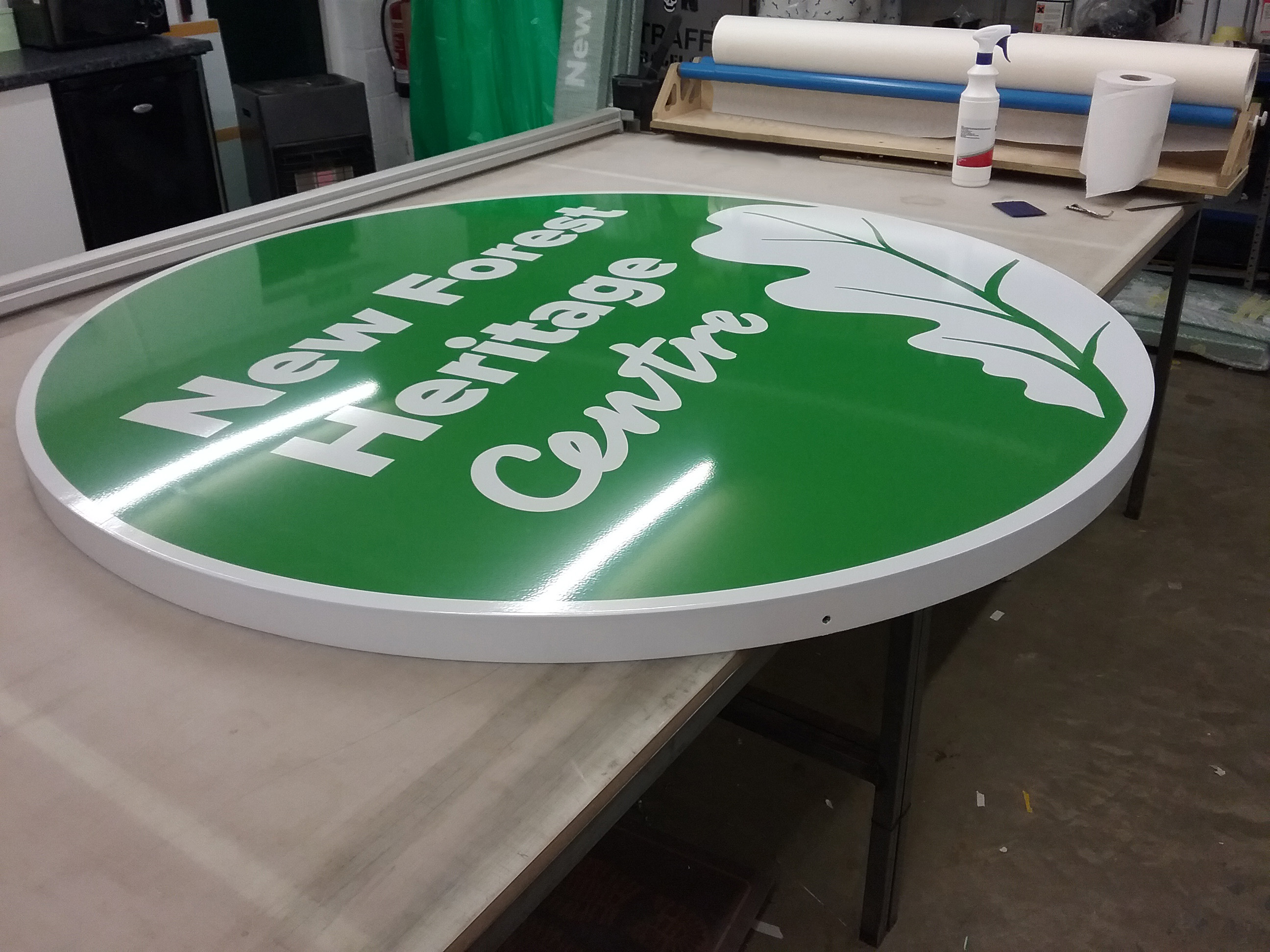 Besoke made circular tray with green vinyl applied to make up company name and decorative leaf design